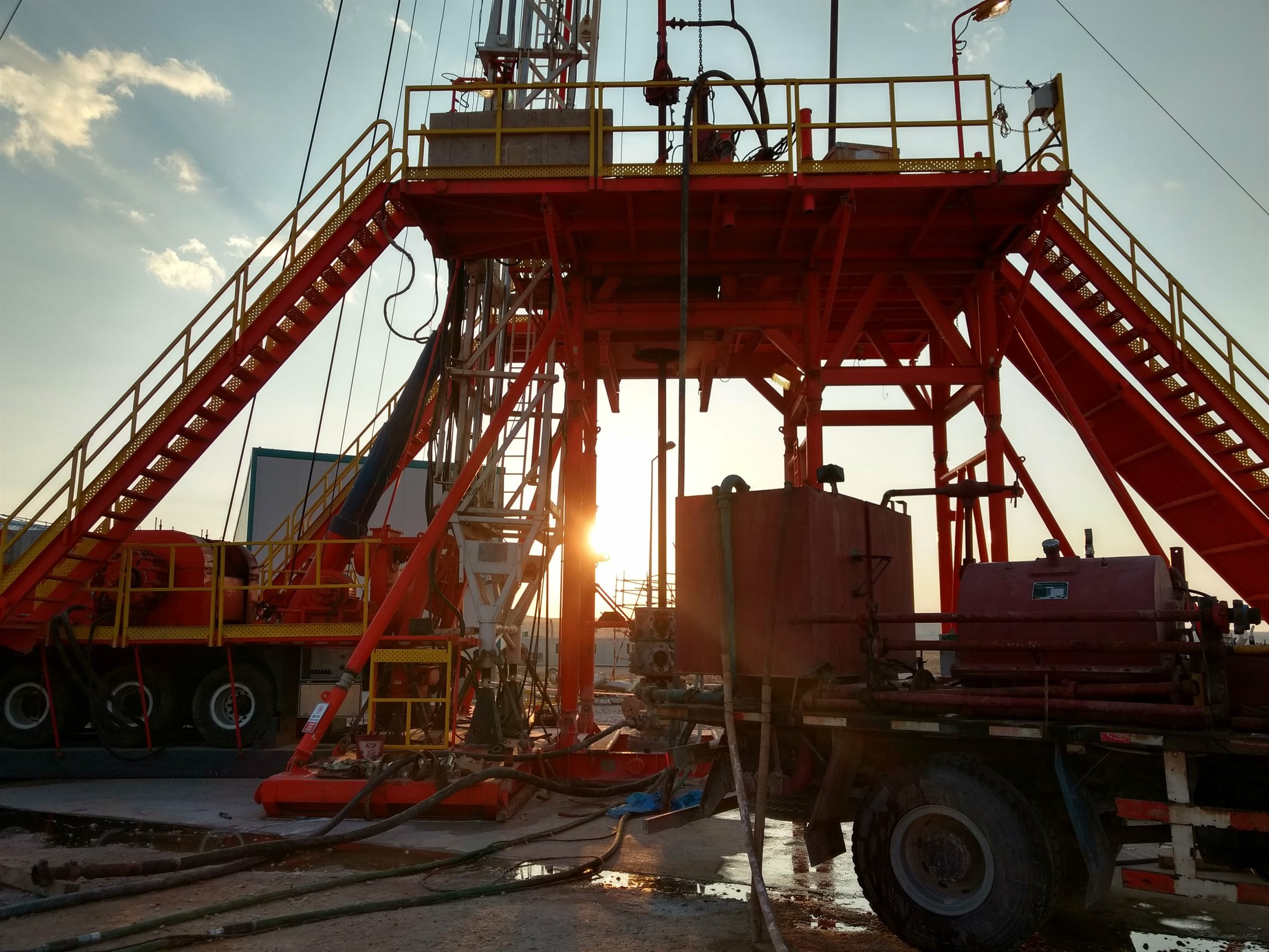 Workover rig at sunset on an oilfield wellsite